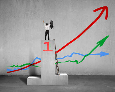 Cheered businessman standing on podium with 3 trends in concreteの写真素材