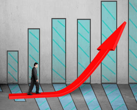 Businessman walking on growing red arrow with chart and concrete backgroundの写真素材