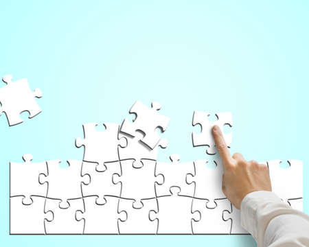 Hand pushing puzzle for assembling in blue background