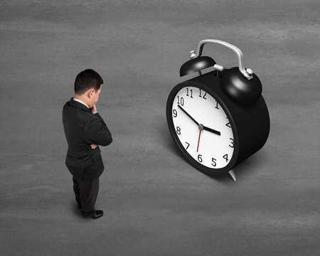 Businessman face alarm clock on concrete ground
