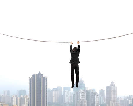 Businessman holding rope and hanging  with city viewの写真素材