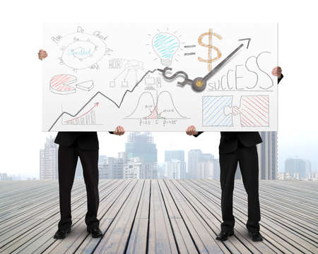 Men Holding board with business doodles and clock hands on wooden floorの写真素材