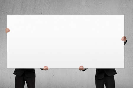 Two men lifting blank board indoorの写真素材