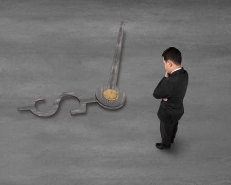 Businessman looking down to money symbol clock handsの写真素材