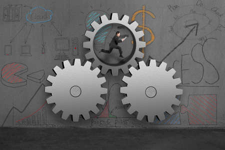 Running in large gears with business doodles on wallの写真素材