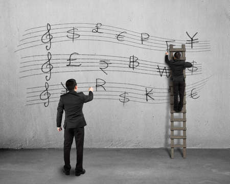 Conducting and another man drawing money stave on concrete wallの写真素材