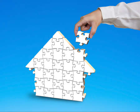 Putting puzzle in house shape blue backgroundの写真素材
