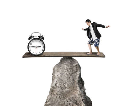 Man balancing against alarm clock at hilltop isolated in white background
