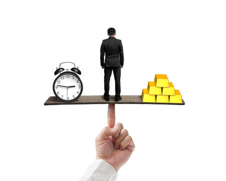standing man between clock and gold balancing on finger seesaw isolated on white backgroundの写真素材