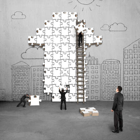 businessman oversee teamwork for puzzles in arrow shape on doodles wallの写真素材
