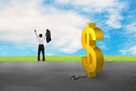 businessman cheering for free from dollar sign shackle with concrete floor and nature skyの写真素材