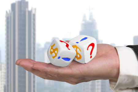 hand giving two white dices with dollar sign and skyscraper background