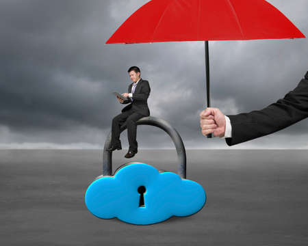 red umbrella protect businessman using tablet on cloud lock with gray cloudy backgroundの写真素材