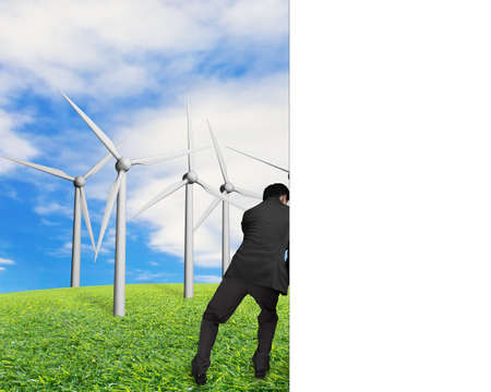 businessman push away white empty wall with nature sky clouds grass and groups of wind turbinesの写真素材