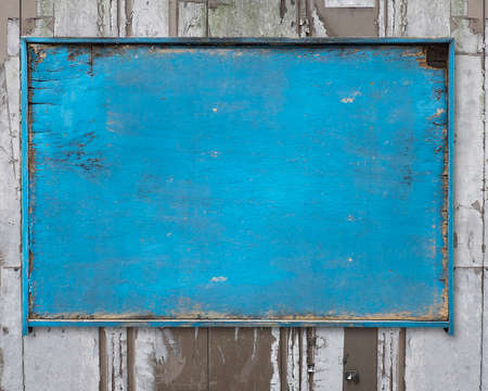 old blue blank weathered wood noticeboard on rough dirty wall backgroundの写真素材
