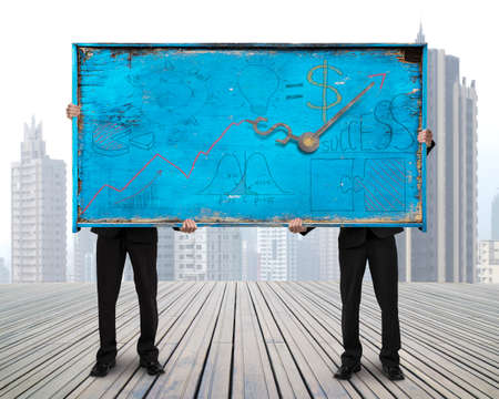 two men holding old blue doodles billboard on skyscraper cityscape background with bussiness growth conceptの写真素材