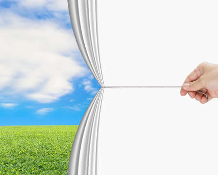 hand pulling open white blank curtain discovered natural sky meadowの写真素材