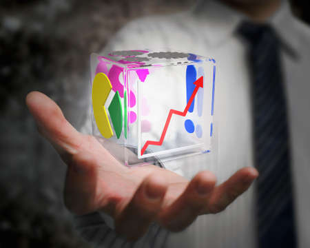 businessman hand holding colorful transparent glass cubic with yellow green pie chart, red up trend line, pink question mark, blue exclamation point, gray gear wheelの写真素材
