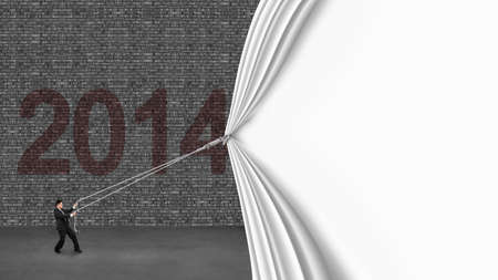 businessman pulling down white blank curtain covering old 2014 brick wall on gray concrete floorの写真素材