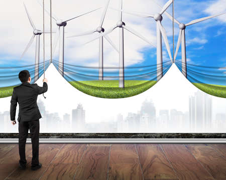 businessman pulling open group of wind turbines curtain covered gray cityscape, environmental...