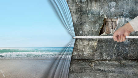 hand pulling natural sandy beach curtain covered old broken wall ruins backgroundの写真素材