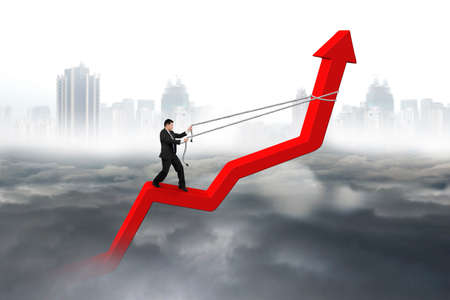Businessman control arrow direction of red trend line with gray cloudy sky cityscape backgroundの写真素材