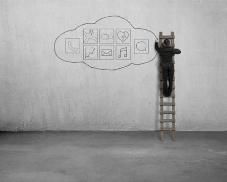 Businessman climbing and drawing app icon on concrete wall backgroundの写真素材
