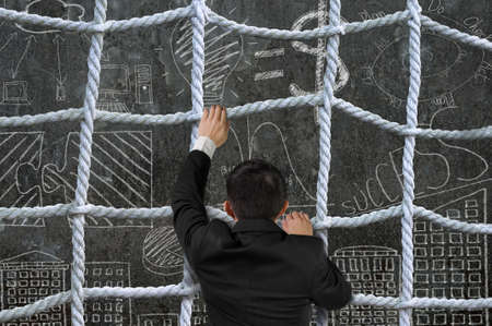 Businessman climbing the crisscross rope net on business concept doodles backgroundの写真素材