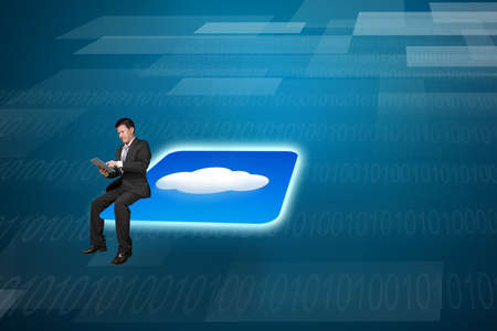 Businessman using tablet sitting on shiny cloud app icon with tech background
