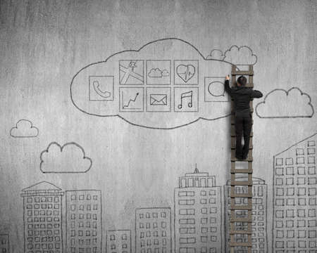 Businessman climbing and drawing cloud app icons doodles on concrete wall backgroundの写真素材