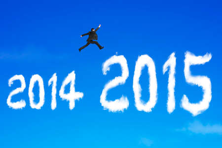 Businessman jumping over 2015 shape cloud on blue sky backgroundの写真素材