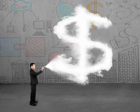 Businessman spraying dollar sign shape cloud paint with business concept doodles wall backgroundの写真素材