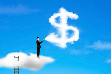 Businessman spraying dollar sign shape cloud paint with ladder and sky backgroundの写真素材