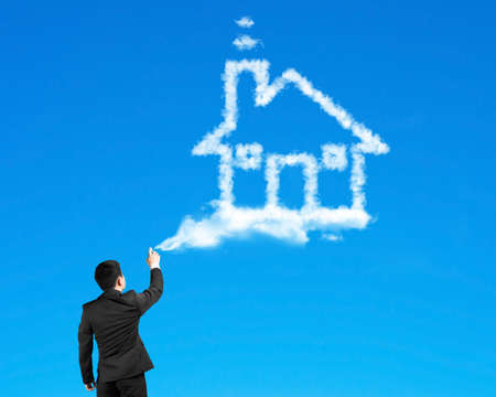 Businessman spraying house shape cloud paint with blue sky backgroundの写真素材