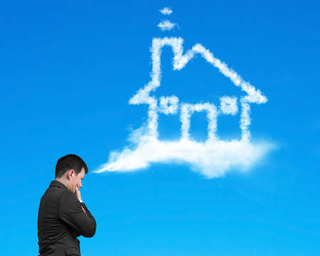 Businessman thinking about house shape cloud with blue sky backgroundの写真素材