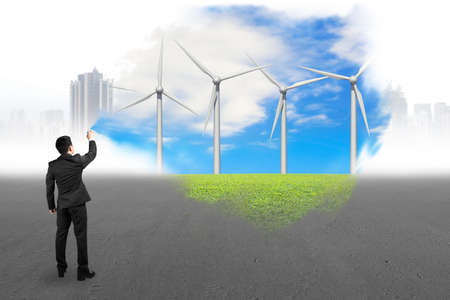 Businessman spraying wind turbines paint covered gray cityscape concrete floor backgroundの写真素材