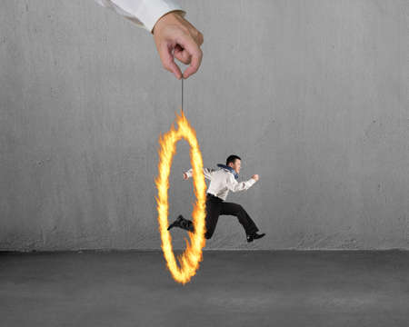 Man jumping through fire circle hand holding with concrete wall backgroundの写真素材