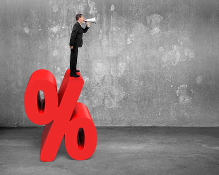 Sales man using megaphone yelling on red percentage sign with concrete room backgroundの写真素材