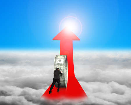 Businessman pushing money circle on red arrow with blue sky sunlight cloudscape backgroundの写真素材
