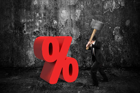 Businessman holding sledgehammer hitting red percentage sign with dark concrete room backgroundの写真素材