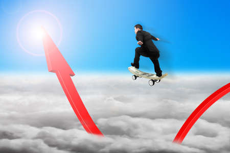 Businessman skateboarding on red arrow pointing up with sunlight cloudscape backgroundの写真素材