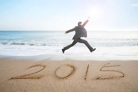 Businessman jumping with new year 2015 on sand beach backgroundの写真素材