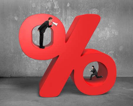 Boss using megaphone yelling at running employee holding tablet with red percentage sign on concrete wall and floor backgroundの写真素材