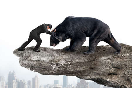 Businessman fighting against black bear on cliff with sky cityscape background
