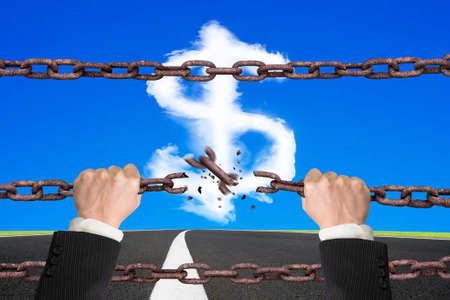 Rusty iron chains broken off by hands with dollar sign shape white clouds on sky asphalt road backgroundの写真素材