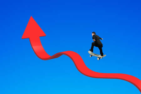 Businessman skateboarding on red arrow up bending trend line with blue backgroundの写真素材