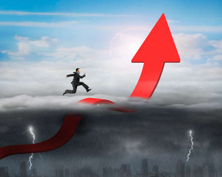 Businessman running on red arrow up bending trend line in the sky with opposite weather conditions background, sunny sky cloudscape, dark overcast lightning raining cityscapeの写真素材