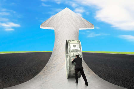 Businessman pushing money circle on arrow up sign marble road with asphalt pavement and sky clouds backgroundの写真素材