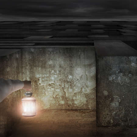 Hand holding vintage lamp illuminated dark maze entrance and cloudy sky backgroundの写真素材