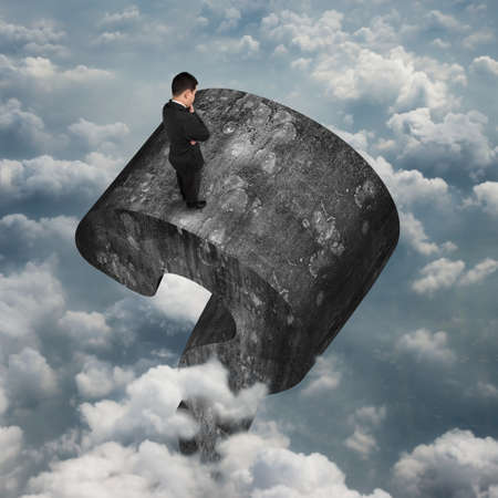 Man standing on top of huge 3D old concrete question mark with sky cloudscape background